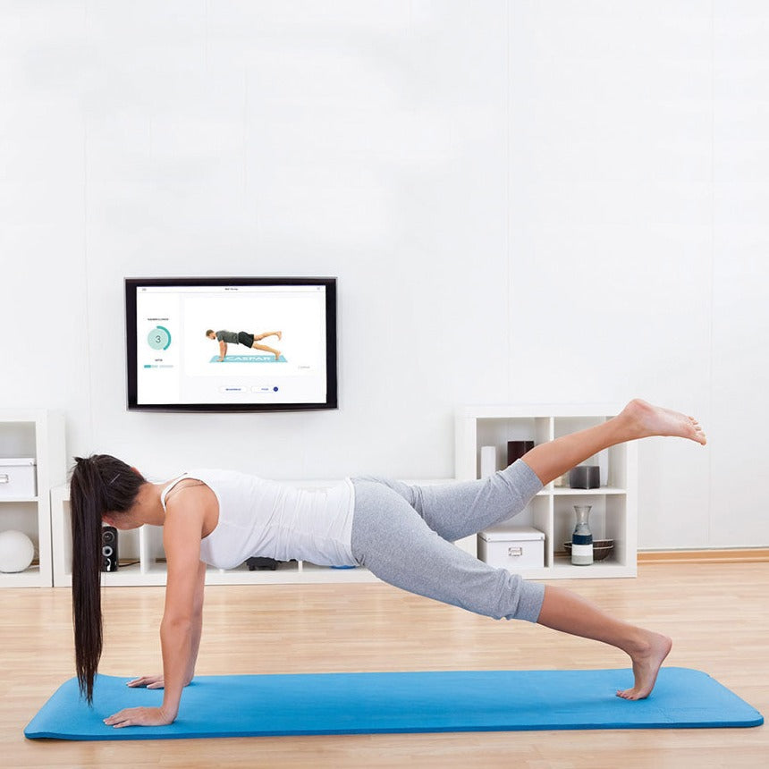 Frau führt zuhause Plank-Übung auf Yogamatte aus, folgt Anleitung auf Bildschirm für präzises Online-Training mit dem ZAR Aalen Tele-Fit-Programm.